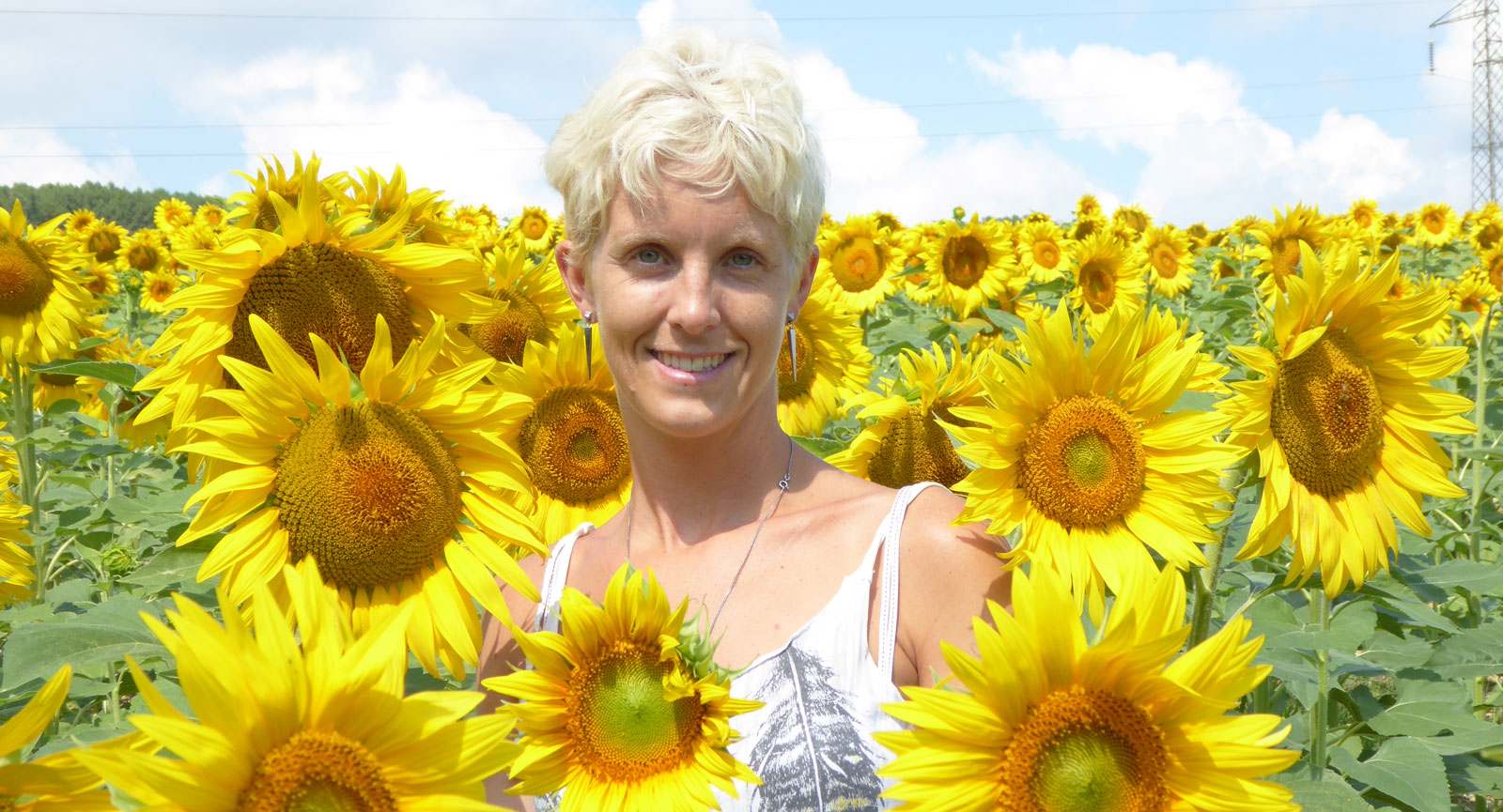 Anna mitt på ett solrosfält i Toskana i norra Italien.