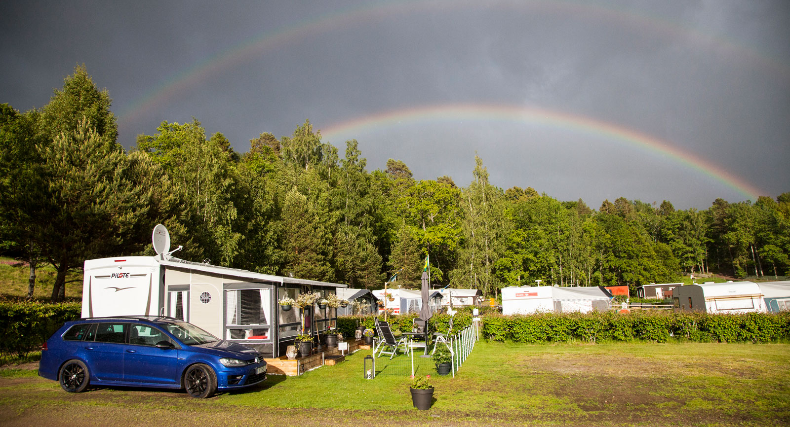 Regnbågen höjer sig över Sandvik Camping och paret Walléns husbilsekipage.
