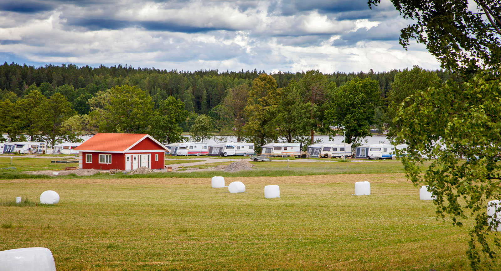 Campingplatserna sedda från åkern med servicehuset i rött.