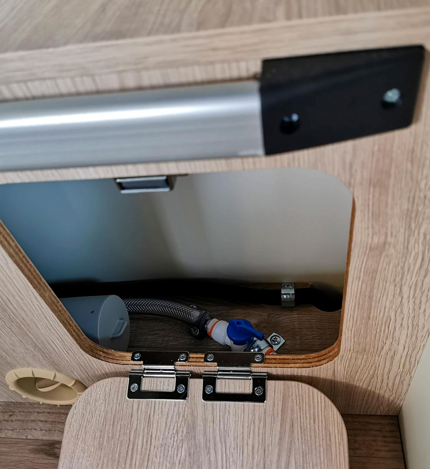 Kranen för tömning av varmvattenberedaren sitter under bordet.