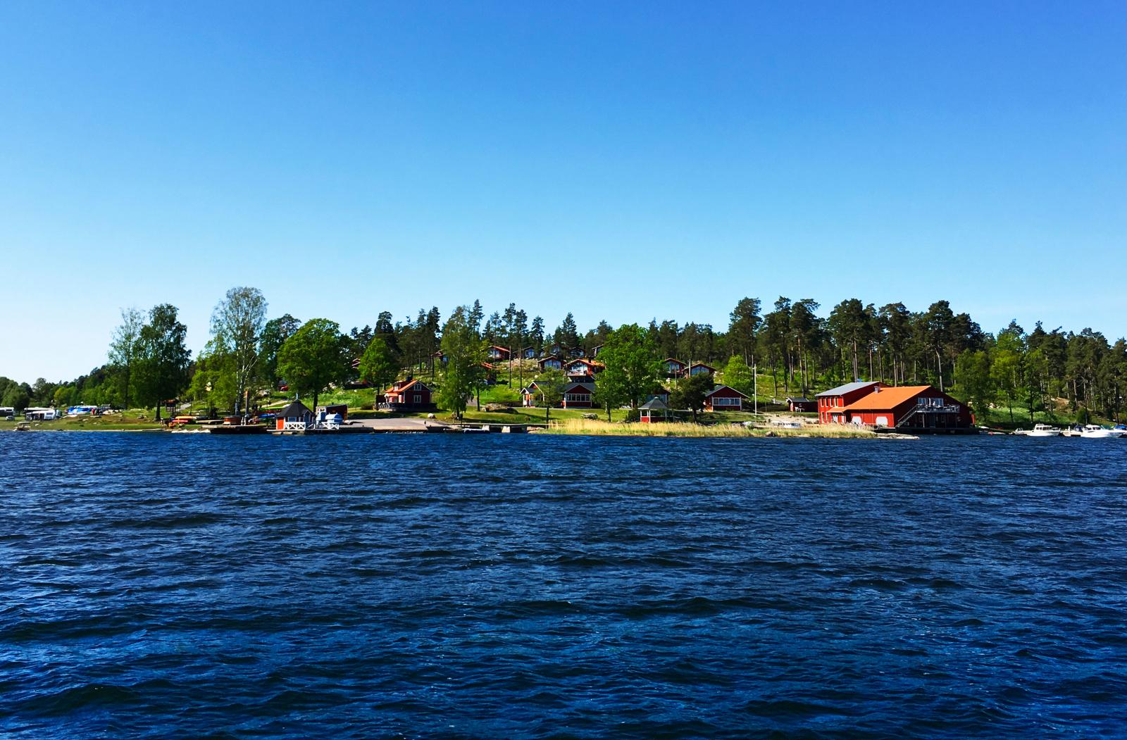 Camping sedd från havet med det faluröda båthuset längst till höger.