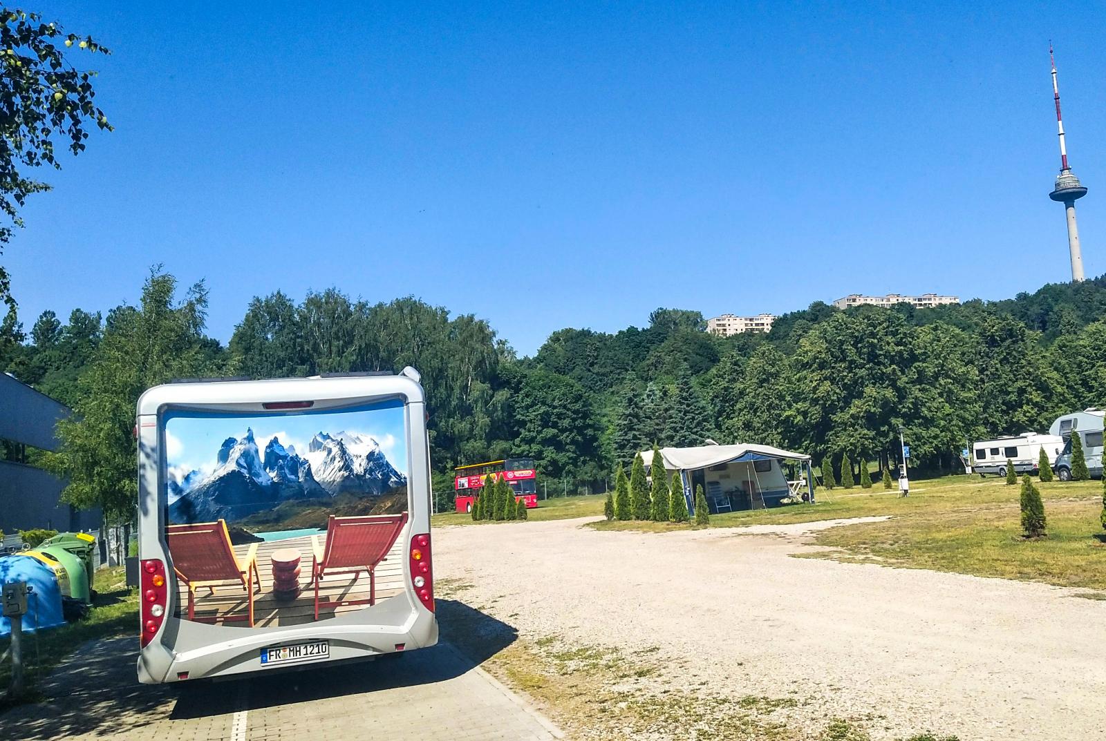 Under högsäsong går en turistbuss med guide från campingen in till centrum. Tv-tornet i bakgrunden är Litauens högsta byggnad med sina 326,5 meter.
