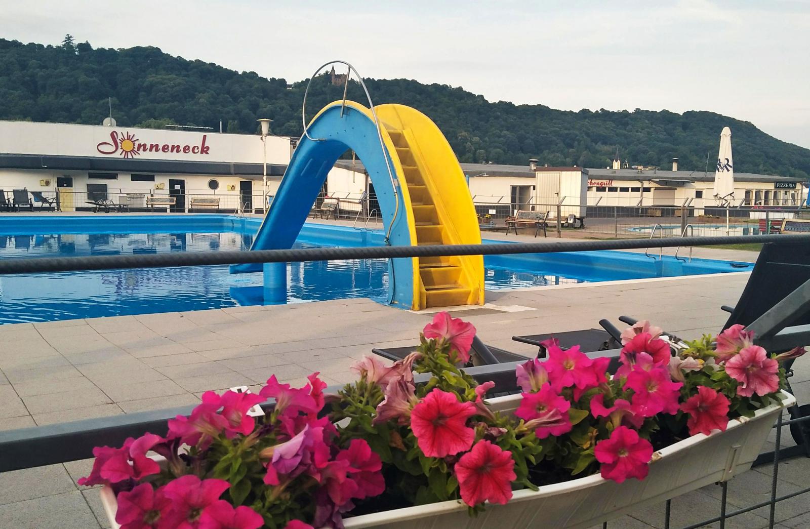 Rejäl swimmingpool med solstolar och rekordkort vattenrutschbana. Plaskdamm för de yngsta till höger.