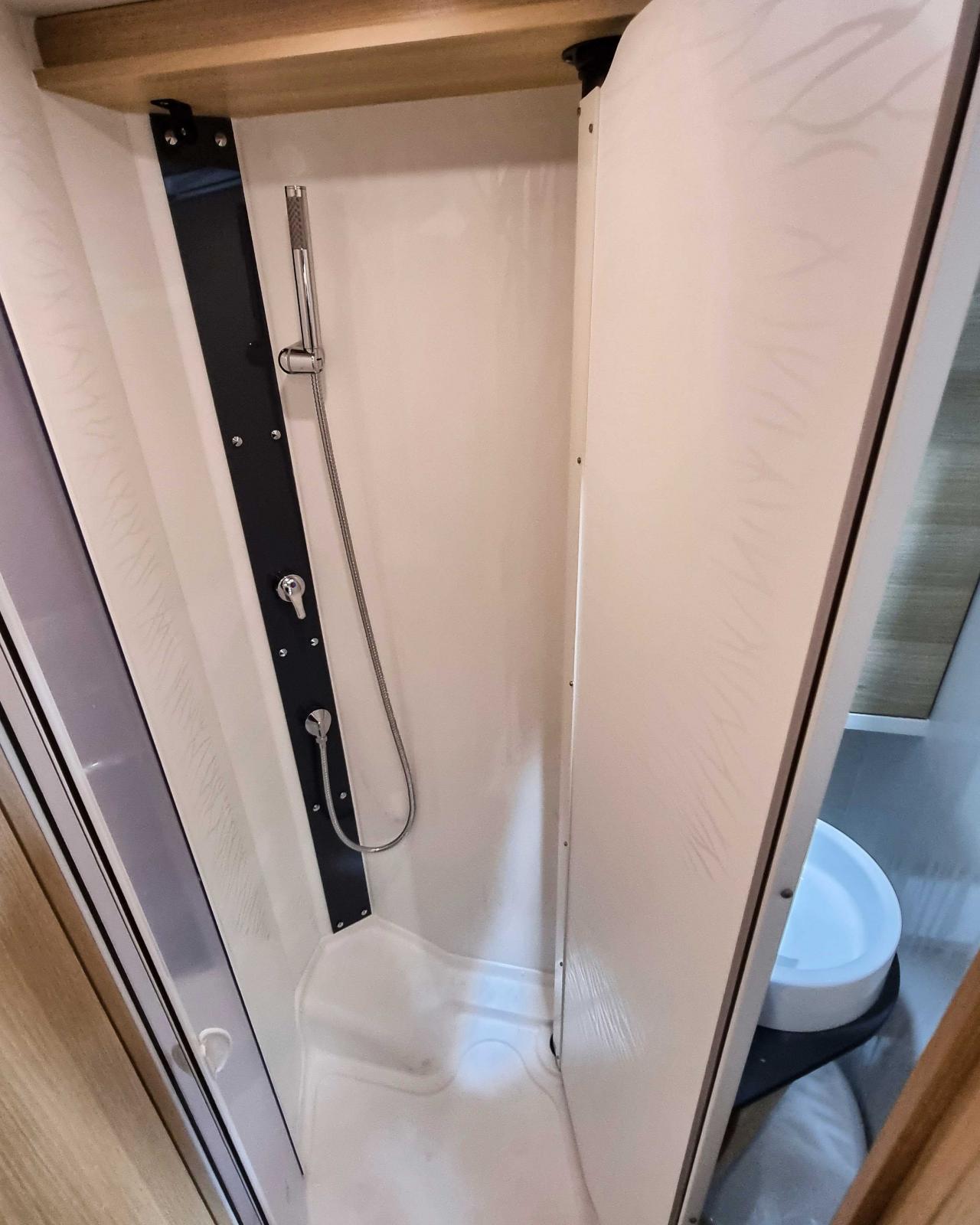 Vikvägg till handfatet som viks över toalettstolen. Det enda som saknas är möjligen förvaring till schampo. Handduken får man hänga på andra sidan väggen.