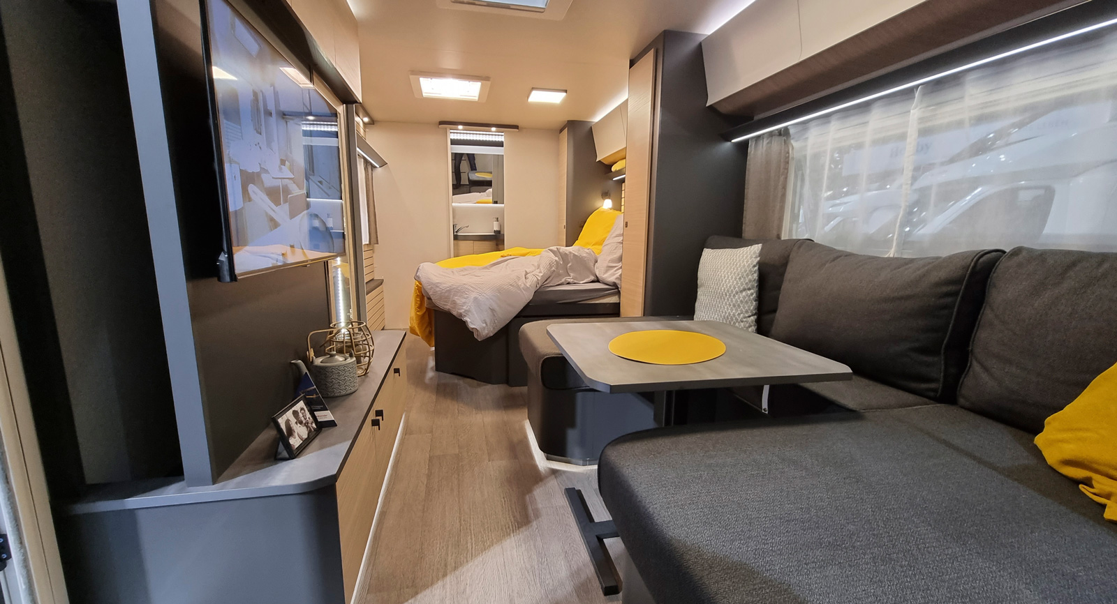 Öppet halloj genom hela vagnen. Dörrlöst hallfack till ytterrocken syns längst till vänster vid entrén. Bäddsoffan har bara ryggstöd mot väggen. Skön tv-soffa för 2-3 personer och kaffe för fyra.