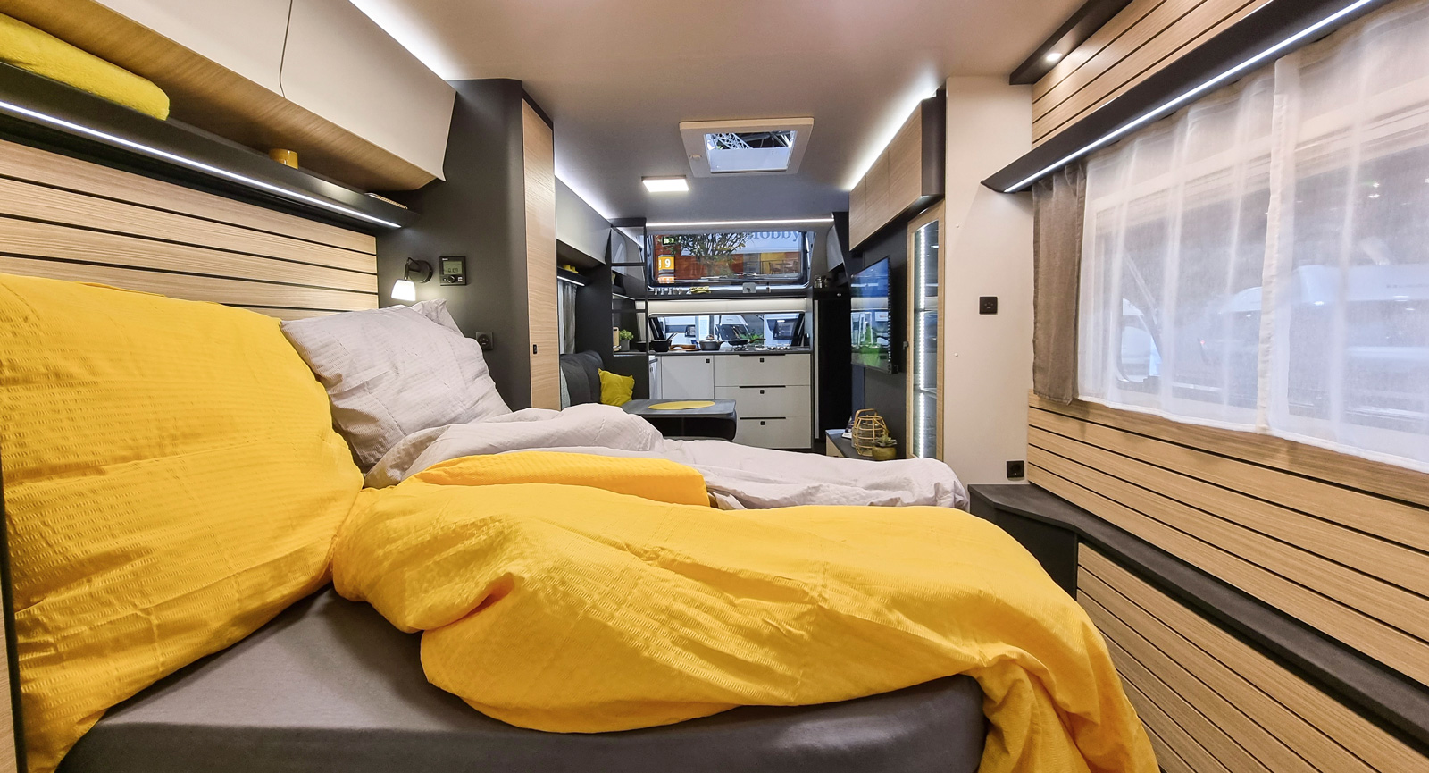 Tvärställd queenbed med hyllor ovanför och garderober på sidorna. Liggande trädekoration återkommer i hela vagnen och ger tillsammans med ljuslister en modern design.