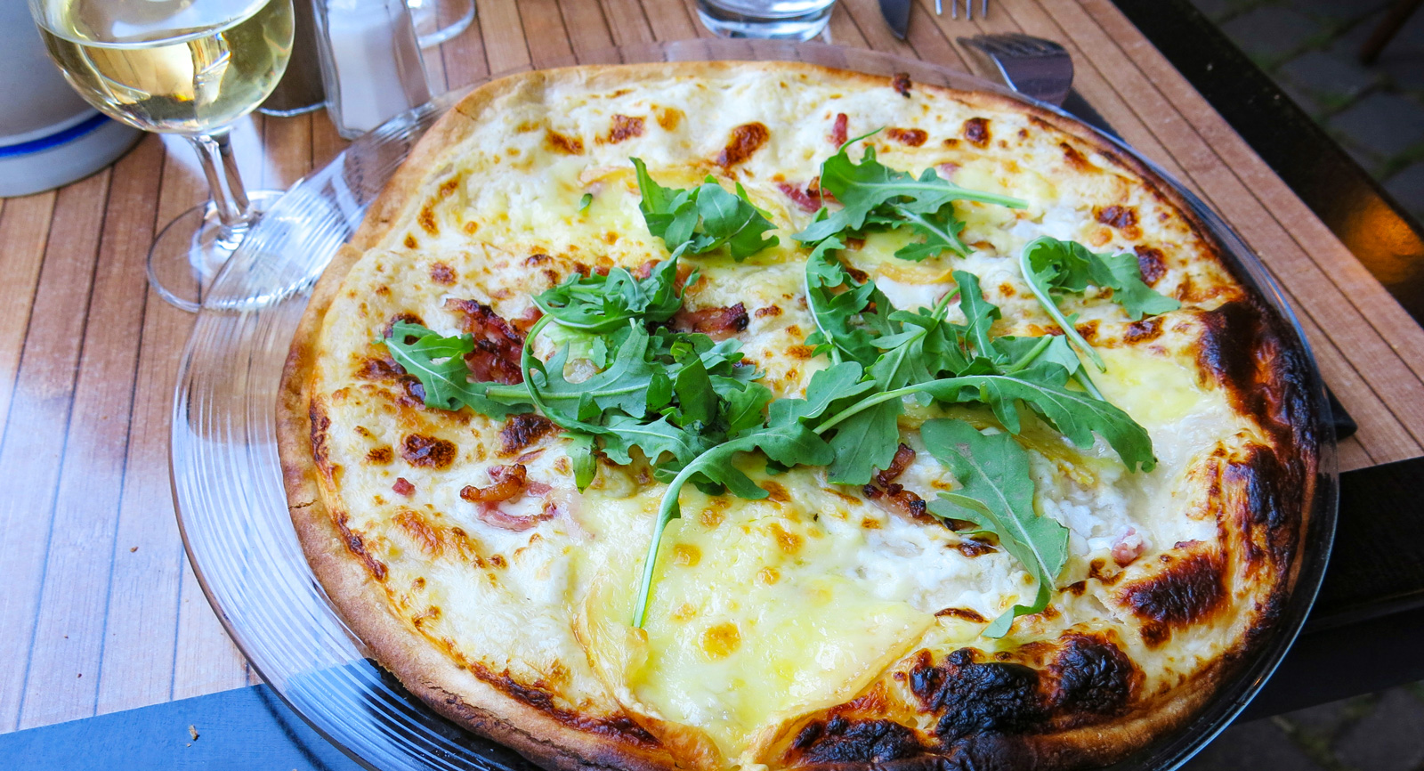 Den alsassiska pizzan, tarte flambée, är gjord på frasig botten och fylld med crème fraîche, rökt skinka och kanske något tillval.