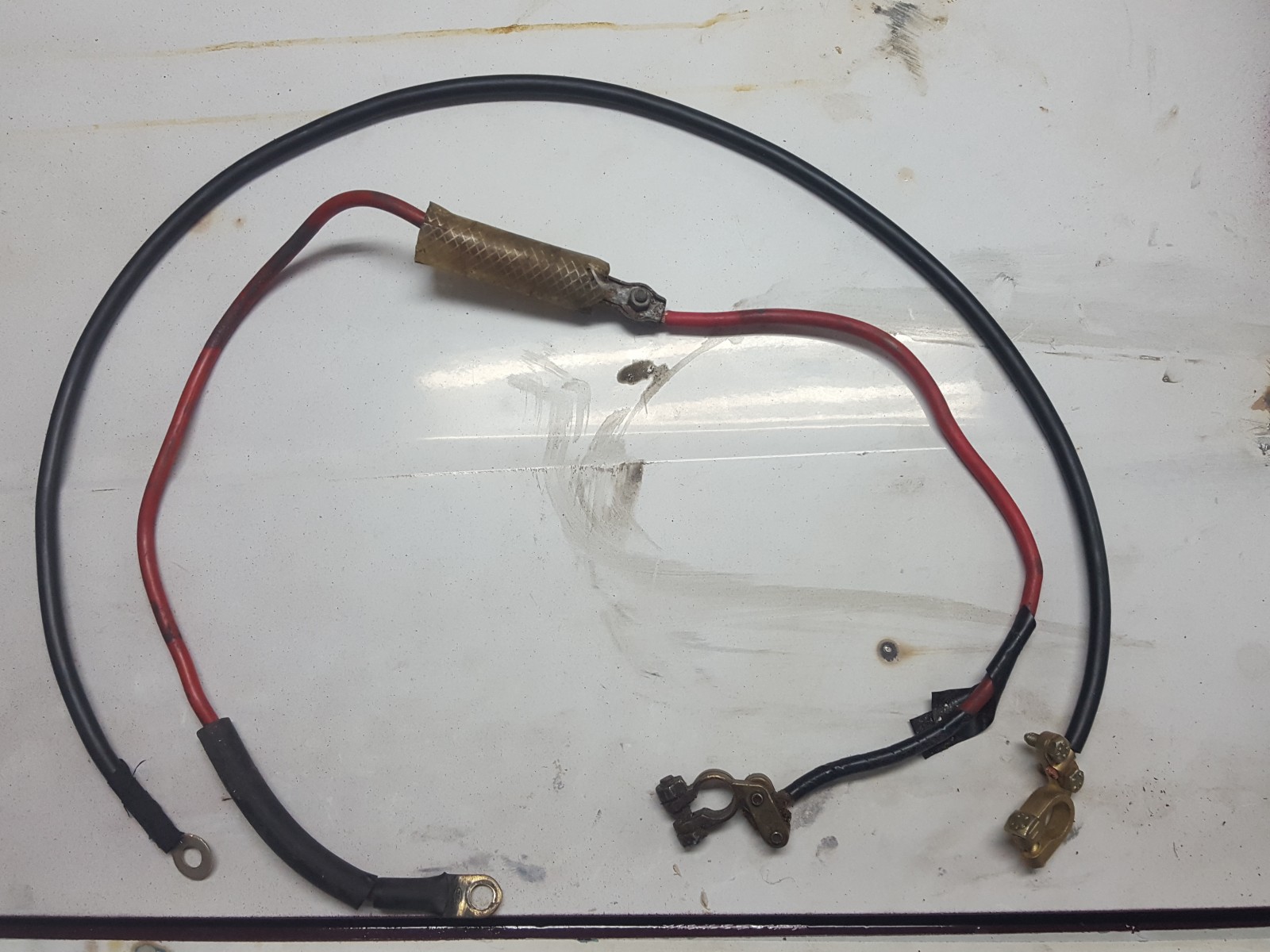 Elsystemet... vi börjar med en enkel sak, batterikabel. Här har man dragit en RÖD minuskabel! dessutom skarvat den och tryckt en bit vattenslang runt...