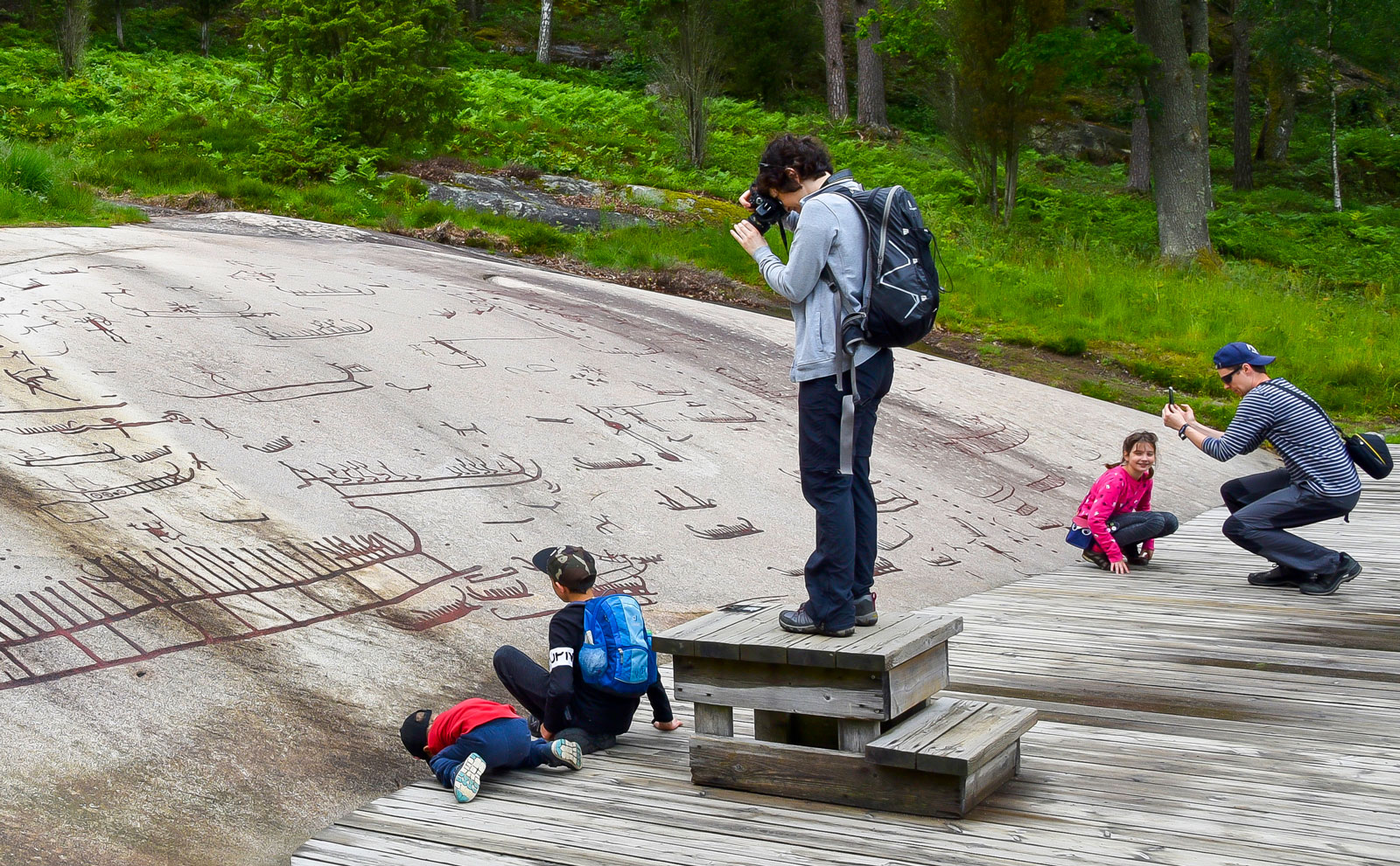 Familjen Gradalski studerar bilderna på Vitlyckehällen som berättar om livet vid havet under bronsålderstid.