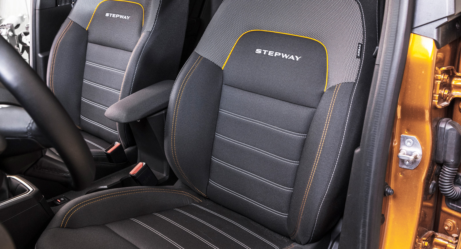 Stol med Stepway-text. Bättre lår- och sidostöd önskas. Mitt-armstöd med förvaringsfack.
