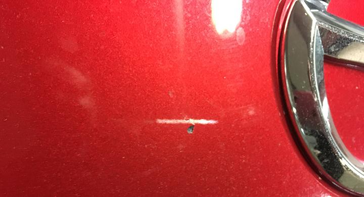 Stenskada i fronten nära emblemet på vår långtest-Miata.